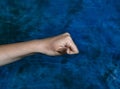 Horizontal shot of a fist with an open thumb pointing at the camera on a marbled blue background Royalty Free Stock Photo