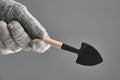 Gardening spade or trowel in human hand with protective gloves isolated on gray background