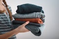 Horizontal shot of a Girl teenager with two braids holding a pile of clothes, isolated on gray background Royalty Free Stock Photo