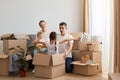 Horizontal shot of happy delighted family unpacking moving box at their new home and playing with cardboard boxes, couple with Royalty Free Stock Photo