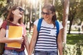 Horizontal shot of happy friends hold hand and have joyful expressions, dressed in casual clothes, hold rucksacks and books, tell