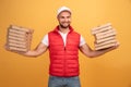 Horizontal shot of happy man holds two piles of carton boxes with pizza, has surprised joyful expression, works as courier in