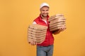 Horizontal shot of happy man holds two piles of carton boxes with pizza, has surprised joyful expression, works as courier in