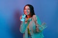 Horizontal shot of joyful adorable Caucasian young girl wearing casual jacket standing isolated over blue neon light background, Royalty Free Stock Photo