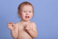 Horizontal shot of little baby boy crying and calling his mother, keeping hands up, looking in distance, being naked, posing Royalty Free Stock Photo