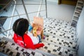 Horizontal shot of a little girl sitting on a stairway and playing on a handmade cardboard laptop