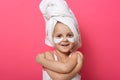 Horizontal shot of little girl with white towel on her head posing isolated over pink background, child female laughs and using Royalty Free Stock Photo