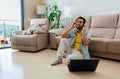 Horizontal shot of a male sitting on the floor in front of a laptop and listening to music Royalty Free Stock Photo