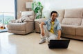 Horizontal shot of a male sitting on the floor listening to music and working with laptop at home Royalty Free Stock Photo