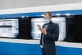 Horizontal shot of male traveler uses public transport for commuting, wears medical mask to protect from coronavirus or covid-19, Royalty Free Stock Photo