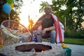 Horizontal shot of middle aged man sitting outdoors eating marshmallows by a fireplace and celebrating fourth of july