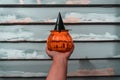 Horizontal shot of a person holding a pumpkin-shaped candle holder with a top shaped like a hat Royalty Free Stock Photo