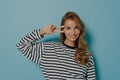 Horizontal shot of pleased lovely young woman with long hair shows peace sign over eye