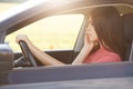 Horizontal shot of prosperous young businesswoman drives car, being in hurry for business meeting, has telephone conversation with