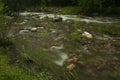 Horizontal shot of a seething river with big stones surrounded by greenery Royalty Free Stock Photo