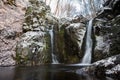 Horizontal shot of several waterfalls coming out of huge snowy rocks in the winter season