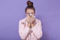 Horizontal shot of sick teenage girl with hair bun wearing casual attire, poses isolated over lilac studio background, woman uses