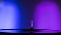 Horizontal shot of a single water drop with purple and blue lighting Royalty Free Stock Photo