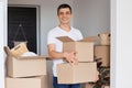 Horizontal shot of smiling man wearing white t shirt standing with cardboard box in hands, looking at camera with smile, being Royalty Free Stock Photo