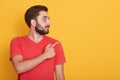 Horizontal shot of smiling young handnsome Caucasian man pointing to empty space aside with his index finger, wearing casual Royalty Free Stock Photo