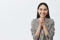 Horizontal shot of stylish happy european girlfriend in jacket, clasping hands together over chest and smiling joyfully