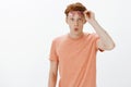 Horizontal shot of surprised and intrigued good-looking ginger man with freckles, taking off glasses and folding lips