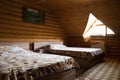 Horizontal shot of two beds in a cabin with a triangle window and a picture on the wall