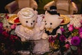 Horizontal shot of two white stuffed bears dressed as bride and groom on a decorated wedding table