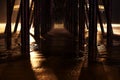 Horizontal shot from under a pier in California coast with creative lighting during the nighttime Royalty Free Stock Photo