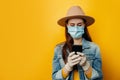 Horizontal shot of woman in medical sterile face mask gloves, chats online with friends, checks notification received on email,