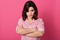 Horizontal shot of young good looking European female isolated over pink background, looks directly at camera with anger, being in