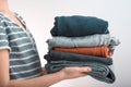 Horizontal shot of a Girl teenager holding a pile of clothes, isolated on gray background Royalty Free Stock Photo