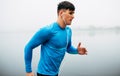 Horizontal side view image of young athelte man running in the morning on the fog lake background. Fitness male exercising in the Royalty Free Stock Photo