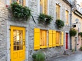 Horizontal side view of 17th Century stone house with bright yellow shutters in the old town