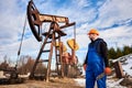 Oil worker in uniform and helmet working in an oilfield next to a pump jack on a sunny day Royalty Free Stock Photo