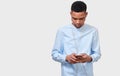 Horizontal studio portrait of African American young man messaging and blogging on cellphone. Royalty Free Stock Photo