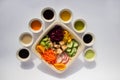 Poke bowl with colorful sauces and fresh vegetables and other tasty ingredients from top view on white background Royalty Free Stock Photo