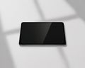 Horizontal tablet device with a dark, reflective screen casting subtle shadows on a light gray surface Royalty Free Stock Photo