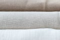 Horizontal textural background of three types of natural linen fabric, rolled up. Selective focus. Closeup view