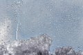 A horizontal texture of water droplets and melting snow and ice is on the glass and on a background of blue sky Royalty Free Stock Photo