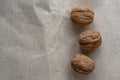 Horizontal. Three inshell walnuts on old peppermint kraft paper, brown background, warm beige pattern