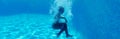 Horizontal underwater photography girl falling in blue water of swimming pool Royalty Free Stock Photo