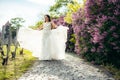 Horizontal view of the beautiful bride playing with the wedding dress near the liliac bushes. Prague location. Royalty Free Stock Photo