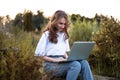 Beautiful young blonde girl lying neargreen grass in park with her laptop and smiling. Royalty Free Stock Photo