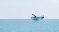 Horizontal view of a blue and white seaplane flying low over the Dry Tortugas to take off