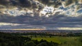 Horizontal view of dramatic puffy clouds over a town surrounded with green fields and  forests Royalty Free Stock Photo