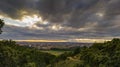 Horizontal view of dramatic puffy clouds over a town surrounded with green fields and  forests Royalty Free Stock Photo