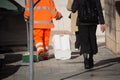 Horizontal View of a Dustman Walking in the Street Beside a Woman, Bringing a Mop and a Bin, Wearing an Orange Uniform