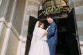 The horizontal view of the happy newlyweds standing near the church. Royalty Free Stock Photo