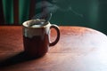 An horizontal view of hot brown cup of ginger tea with steam, tea bag and spoon on rustic wooden table Royalty Free Stock Photo